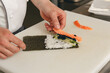 Chef hands cooking sushi with rice, salmon and nori on kitchen of japanese restaurant