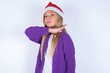 little kid girl with Christmas hat wearing yarn jacket over white background cutting throat with hand as knife, threaten aggression with furious violence.