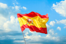 Waving Flag Of Spain Against Blue Sky