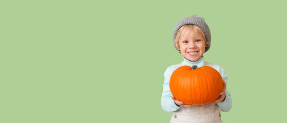 Wall Mural - Cute little boy with autumn pumpkin on green background with space for text