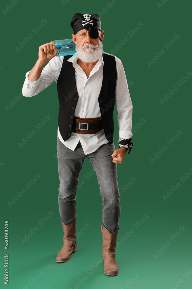 Old pirate with bottle of rum on green background