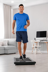 Canvas Print - Sporty man training on walking treadmill at home