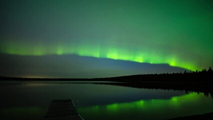 Wall Mural - streams of aurora dance across a star filled sky and reflect in a calm lake in this time lapse.