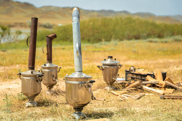boiling samovar in the steppe with fire wood. catering travel outdoor.
