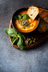 Wall Mural - Pumpkin soup with bread, seeds and basil leaf on dark background