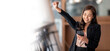 © NAMPIX - Happy Asian woman holding a smartphone, raise hand up and exciting with good news. Banner background.