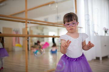 Little girl with down syndrome at ballet class in dance studio. Concept of integration and education of disabled children.