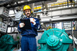 © littlewolf1989 - Power plant maintenance worker standing by gas generators turbines and doing inspection of production.