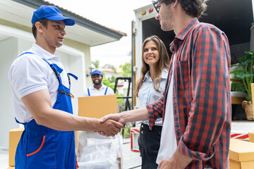 Men mover worker in blue uniform and Homeowner making handshake to work success moving to new house.Homeowner checking delivery list cardboard.african american Worker unloading boxes from van outdoors