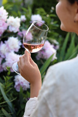 Wall Mural - Woman with glass of rose wine in peony garden, closeup