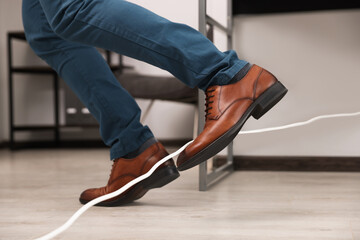 man tripping over cord in office, closeup