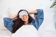 © Meeko Media - A young multi-ethnic woman stretches with arms behind head and sleep mask