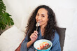 © Meeko Media - A beautiful multi-ethnic woman eats fruit bowl in bed licking the spoon