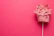 Horizontal image of homemade pink candy floss on stick, on pink background with copy space