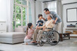 © MAGNIFIER - Family members are caring and encouraging a grandfather who is sick and unable to walk in a wheelchair.