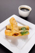 Close up of asian spring rolls on white plate and soy sauce on grey background