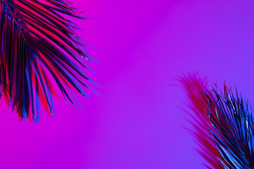 Image of vibrant neon lit pink leaves over pink to purple background with copy space