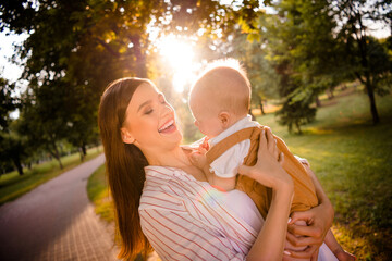 Poster - Photo of positive cheerful mom mommy lady playing cuddle with infant toddler on outside green public park