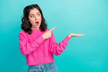 Poster - Portrait photo of young attractive pretty woman funny look directing finger hold hand empty space shock information isolated on cyan color background