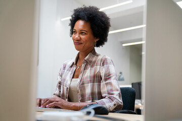 Young business woman working on desktop computer at modern startup office