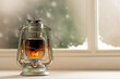 Vintage christmas shining oil lantern over frozen and snowy window