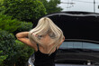 © Mikhail - young blond woman straightens her hairstyle near the car