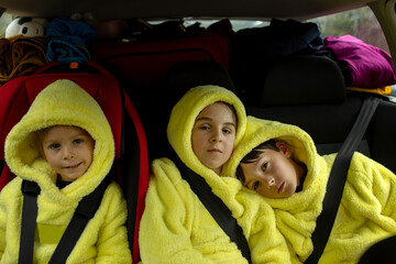 Wall Mural - Three boys in car seats, traveling in car, looking at camera, going on vacation