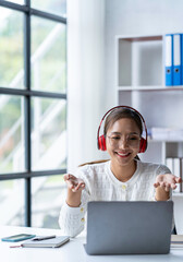 Study Study. Asian woman wearing headphones using laptop computer at home, work