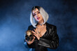 sexy woman in halloween costume holding golden skull on dark background with blue fog.