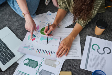 Aufkleber - above view of hands of two young businesswomen discussing documents with graphic financial data on t