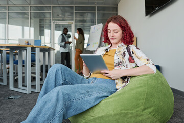 Aufkleber - Young serious employee in casual attire sitting in armchair and networking or preparing for presentation in office
