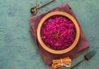 Stewed red cabbage with spices in a clay dish on a green concrete background. Traditional Christmas food.