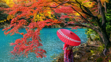 Wall Mural - Asian woman wearing japanese traditional kimono at Arashiyama in autumn season along the river in Kyoto, Japan.