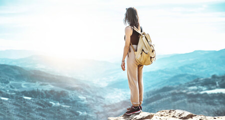 Wall Mural - Woman hiker with backpack standing on the top of the mountain looking the scenic view - Traveler enjoying nature - Sport and journey concept
