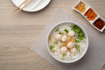 Wall Mural - Rice vermicelli Noodle soup with pork balls in white bowl.Top view