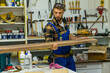 © DusanJelicic - Handsome carpenter carries the long board through workshop