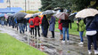  Ludzie pod parasolami czekają w kolejce do mobilnego punktu szczepień we Wrocławiu