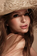 Portrait of a beautiful woman in a straw hat, loose hair and nude makeup. Beauty face