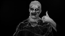 Sinister Man With Scary Halloween Zombie Makeup In Costume Raises Thumbs Up Agrees With Something Or Gives Positive Reply Recommends Advertisement Likes Good. Dead Guy With Wounded Bloody Scars Face