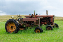 A Pair Of Old Rusty Tractors In A Field
