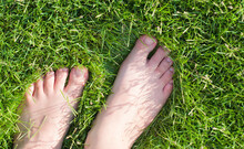 Woman Barefoot Standing On Green Grass At Sunshine