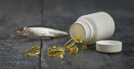 Wall Mural - Fish oil capsules spilling out of a bottle on a wooden table.