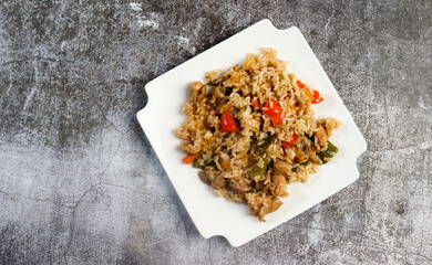 Wall Mural - Chicken Bell Pepper Rice on a white square  plate on a dark background. Top view, flat lay