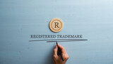 Fototapeta  - Letter R cut into wooden cut circle and male hand writing a Registered trademark sign under it