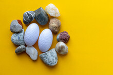 Stone Nest And Two Plastic Eggs On Yellow Background. Archeology Concept