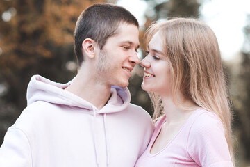 Happy smiling teenager boy 18-19 year old having fun with teen girl together outdoor. Look at each other. Autumn season. Positive emotions.