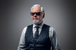Portrait of cool old man with sunglasses dressed in waistcoat and white shirt.