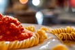 Closeup of a plate of rotini pasta dish with tomato sauce