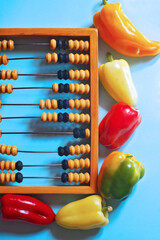 Wooden abacus on a blue background with bell pepper