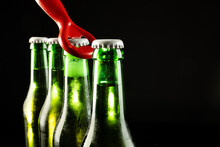 Image Of Red Bottle Opener And Four Green Beer Bottles With Crown Caps, With Copy Space On Black